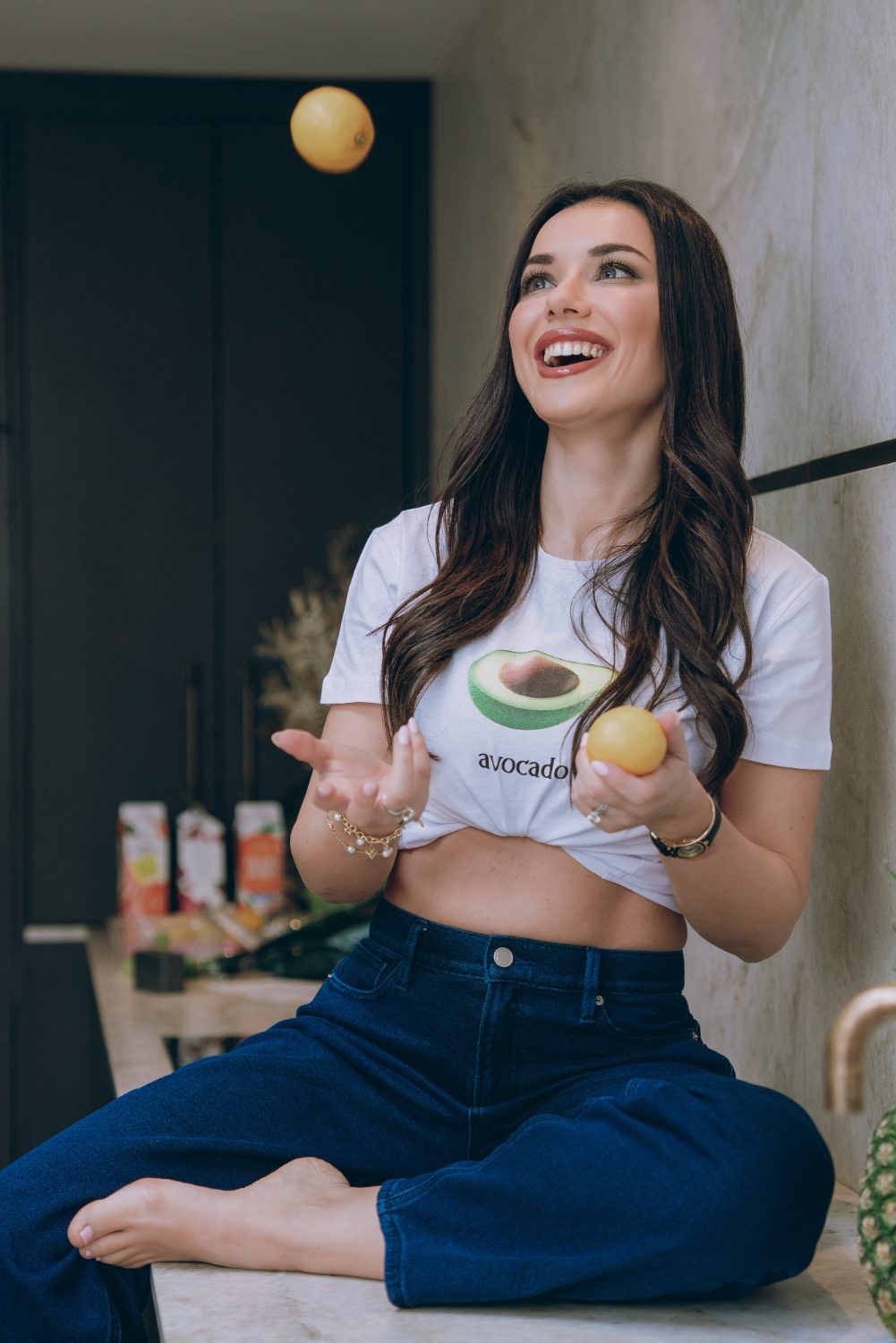 Selen laughing in her kitchen, tossing a lemon into the air